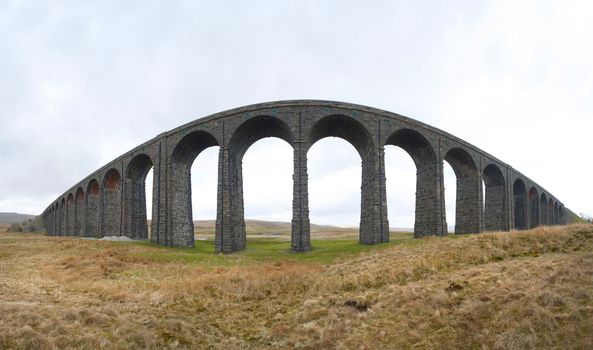 Wide angle panoramic view of the old stone arches of the Victorian railway viaduct over the River Ribble known as the Ribblehead Viaduct, North Yorkshire