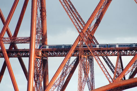 close up on train crossing the forth bridge showing the complex structure of metal tubes and girders