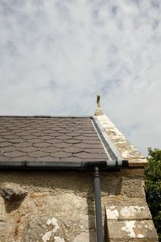 A diamond cut slate roof with ridge tiles and a lead valley edge running to a gutter.