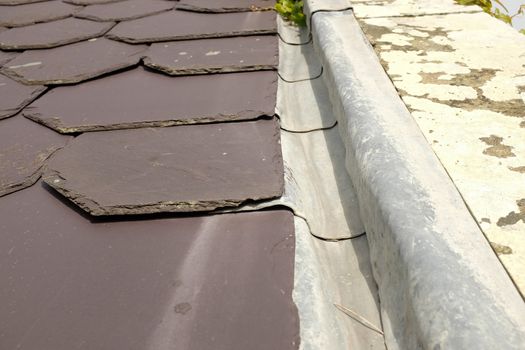 A cut slate roof with a lead valley edge under-lapping the slates.