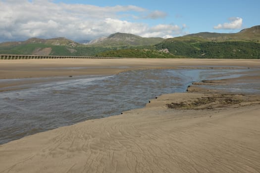 Patterned sand and a river looks out across the Mawddach estuary with the mountain Cadair Idris in the distance, Gwynedd, Wales, UK.