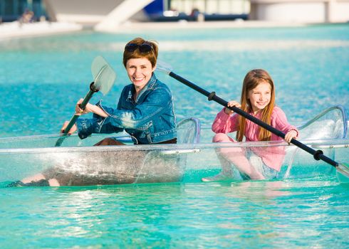 Little girl with her mother in a transparent kayak ride