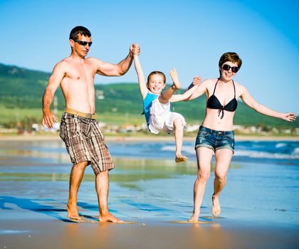 Beautiful family with daughter playing on the beach