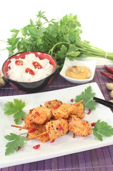 Asian satay skewers with rice and chili on a light background