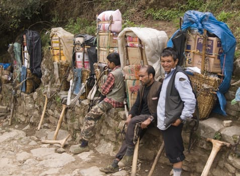 Porters resting next to the very heavy loads they are carrying in the Himalaya Mountains, Nepal