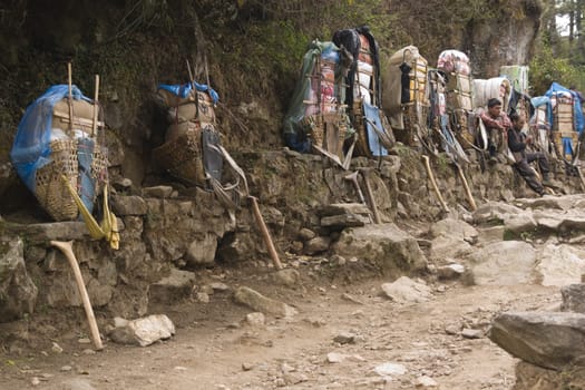 Porters resting next to the very heavy loads they are carrying in the Himalaya Mountains, Nepal