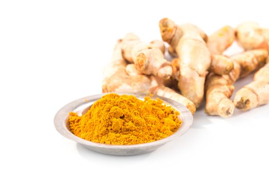 turmeric powder with fresh turmeric root on white background