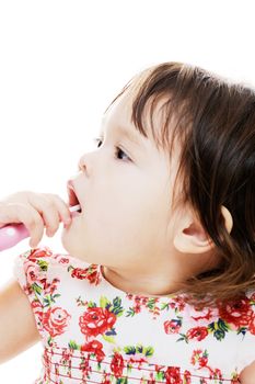 young girl cleaning her teeth with pink toothbrush