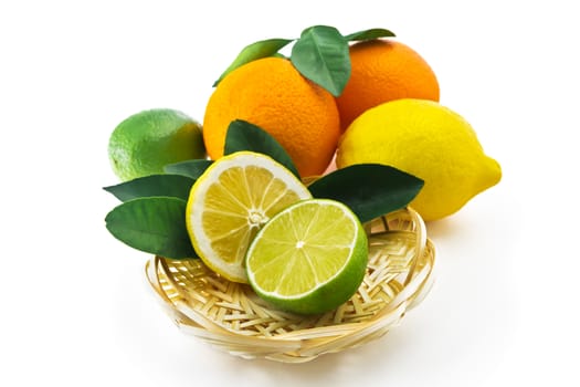 Orange, lemon, lime and half with leaves on a wicker saucer