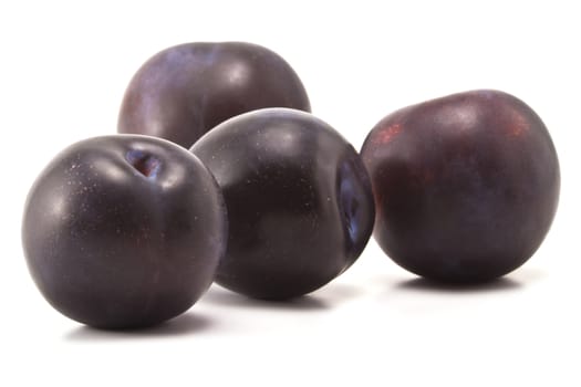 Four ripe plums on a white background