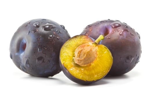 ripe plums and plum part of a bone on a white background