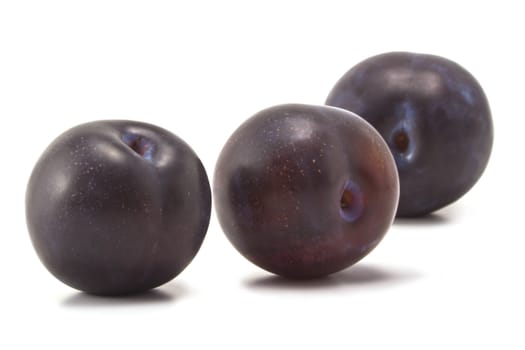 Three ripe plums on a white background