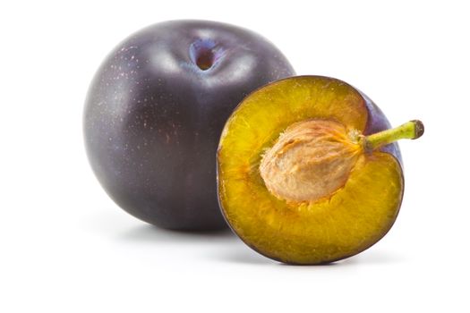 ripe plums and plum part of a bone on a white background