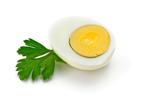 one half of boiled egg with parsley leaves on a white background