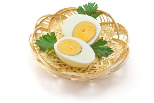 two halves of boiled eggs and parsley leaves in a straw plate