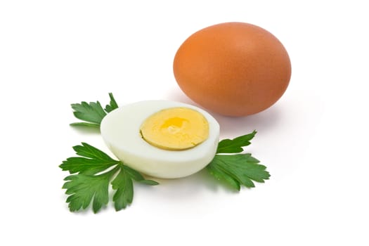 one egg and half of boiled egg with parsley leaves on a white background