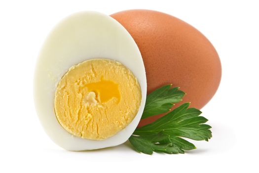 one egg and half of boiled egg with parsley leaves on a white background