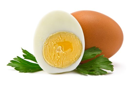 one egg and half a boiled egg with parsley leaves on a white background