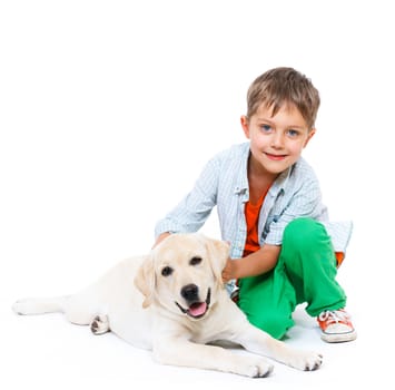Cute little boy kneeling with his puppy labrador smiling at camera on white background