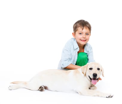 Cute little boy kneeling with his puppy labrador smiling at camera on white background