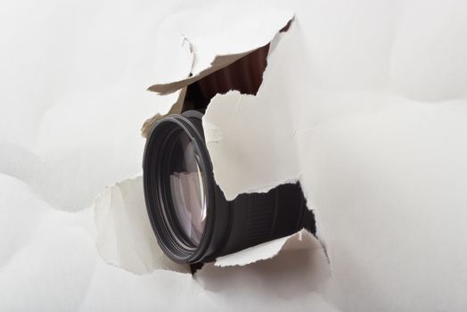 photo lens protruding through a hole paper