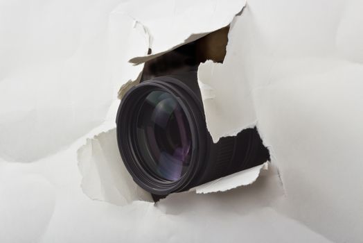 photo lens protruding through a hole paper