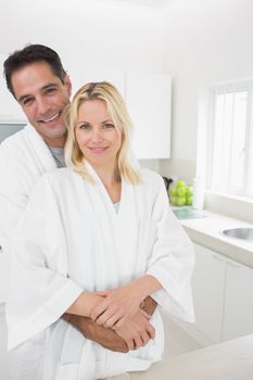 Portrait of a man embracing woman from behind in the kitchen at home