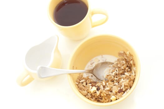 High angle view of a healthy bowl of muesli cereal served with milk and a mug of freshly brewed coffee for breakfast on a white background