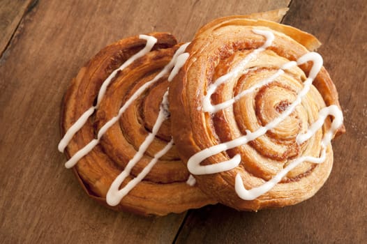 Freshly baked spiral Danish pastries with flaky puff pastry filled with apple or almond paste and drizzled with white icing for a delicious sticky sweet snack or dessert