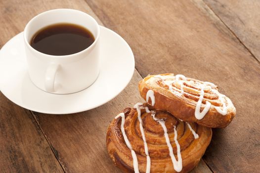 Freshly brewed full roast cup of filter or espresso coffee served with flaky fruity Danish pastries drizzled with icing sugar for a tasty coffee break
