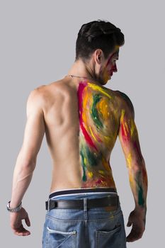 Handsome young man seen from the back with skin all painted with holi colors