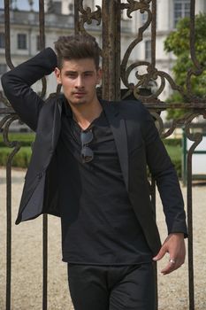 Handsome young man outdoors, old elegant royal palace behind him (Stupinigi Palace in Turin, Italy)