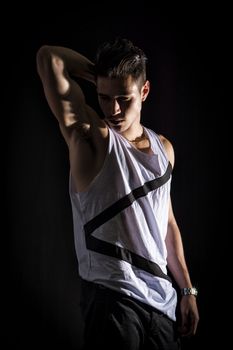 Portrait of handsome young man in white tank-top isolated on black. Dramatic lighting