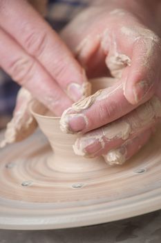 Hands of a potter, creating an earthen jar on the circle