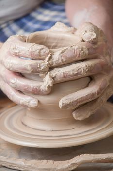 Hands of a potter, creating an earthen jar on the circle