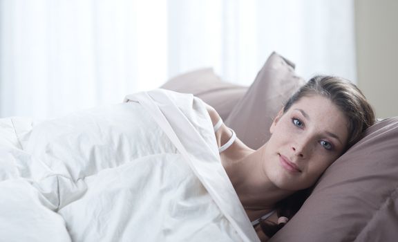 A gorgeous young woman while lying in bed 