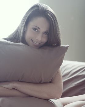 Young woman embracing her pillow in the morning