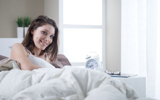 Young woman smiling while lying in bed 