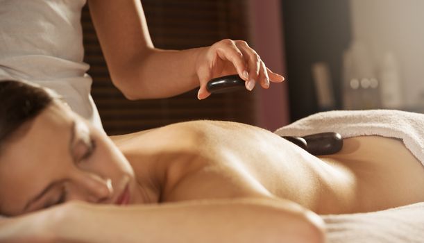 Attractive woman receiving a relaxing hot stone massage on her back.
