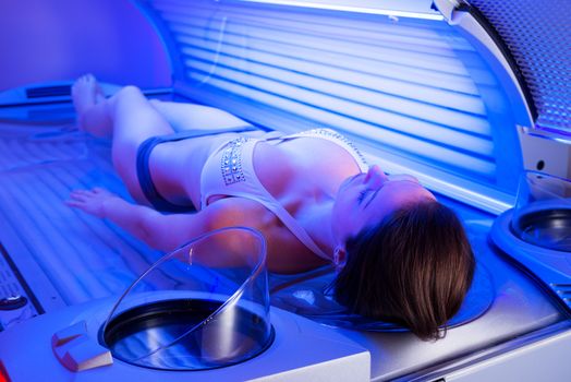 Attractive woman relaxing and sunbathing on tanning bed.
