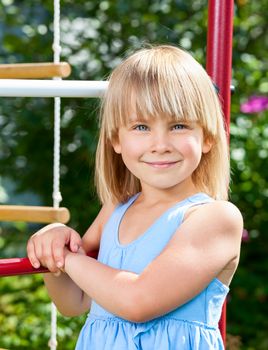 Portrait of cute little girl standing at monkey bars