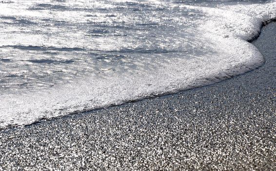 Water in slow motion to the beach in Varna, in the reflection of the sun