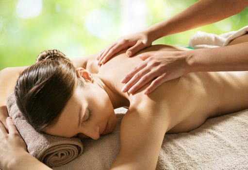 Beautiful woman receiving a relaxing back massage at spa.