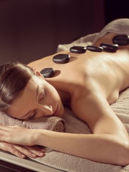 Young woman receiving a lastone spa treatment and relaxing.