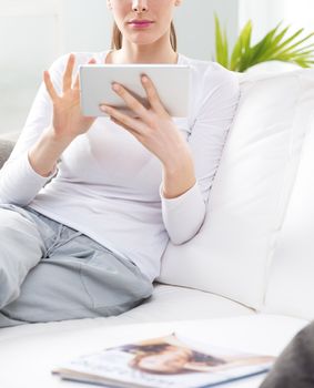 Woman relaxing in the living room using digital tablet.