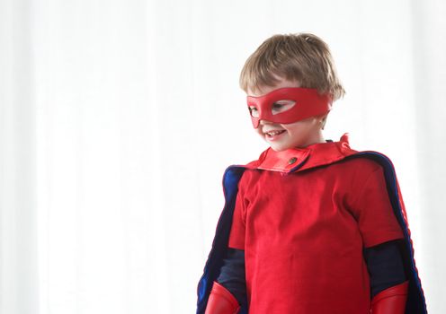 Smiling super hero kid with red mask and cape close up.