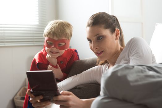Mother and superhero child playing videogames together in the living room.