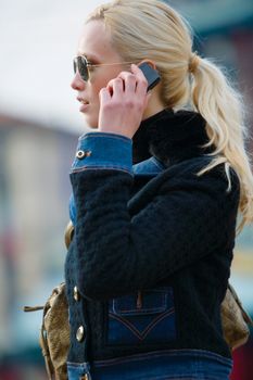 young girl speaks by mobile phone in the street