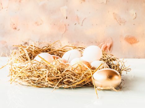 One golden egg and eggs in the nest on glass gray and on wood background