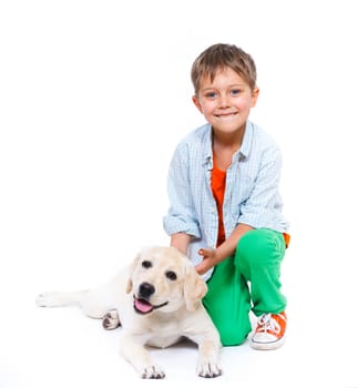 Cute little boy kneeling with his puppy labrador smiling at camera on white background